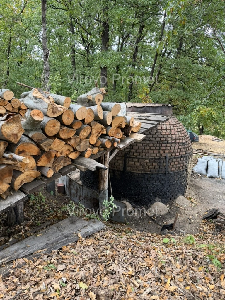 Logs stacked beside a brick kiln